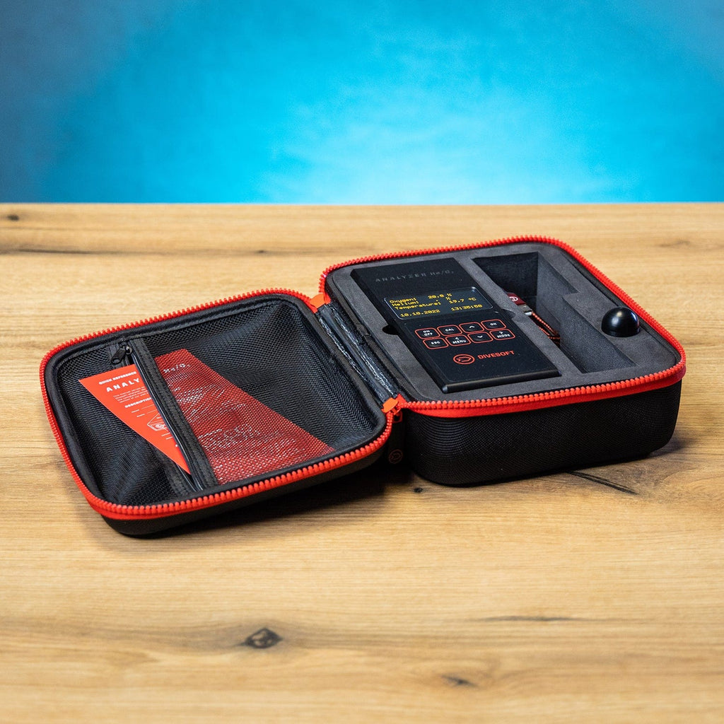 Open black case with red trim, containing a device and documents.